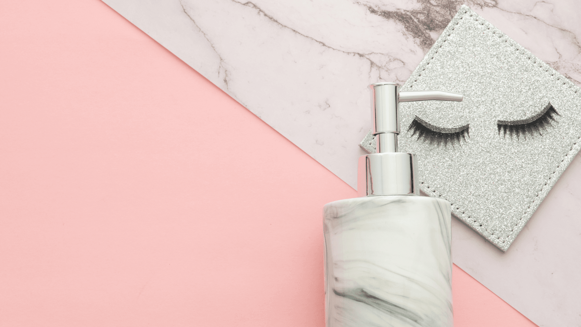 False eyelashes with a shampoo bottle on a pink background