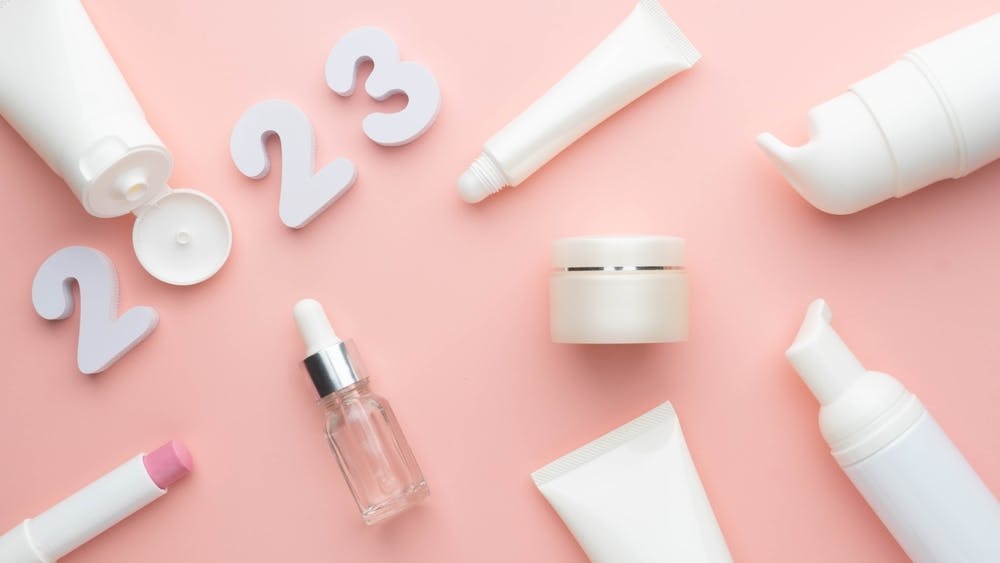 "2023" surrounded by cosmetic products on a light pink background