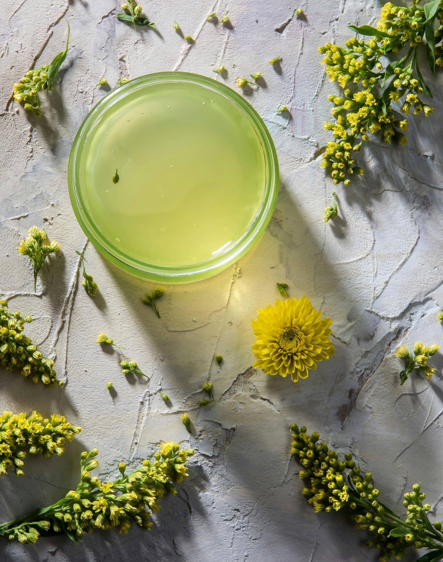 Pale green gel in a jar, surrounded by flowers